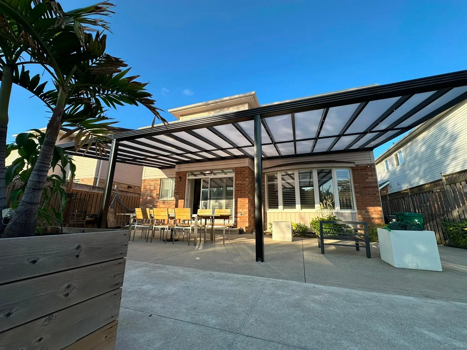 Dark-framed pergola extending a residential patio into an outdoor seating area